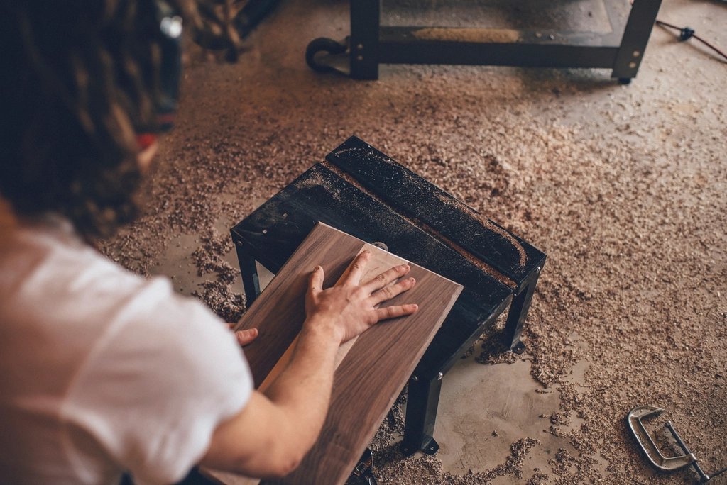 Craftsman sanding a solid walnut piece in a workshop — bespoke joinery and fit-out