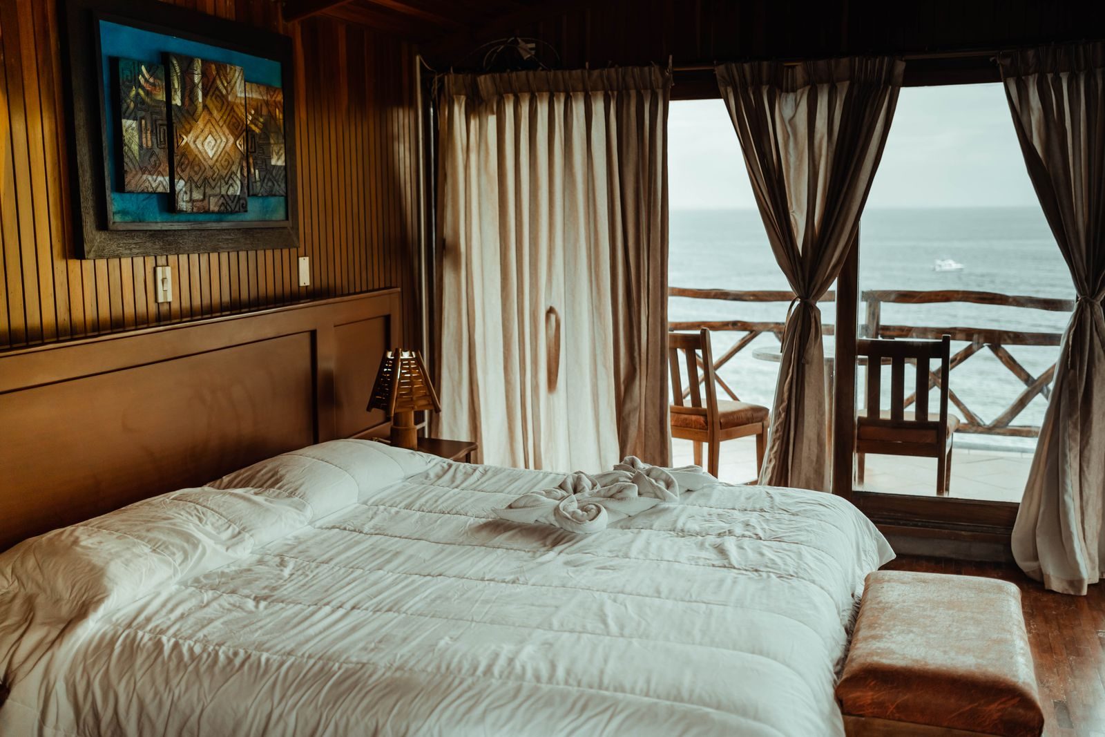 Chambre d'hôtel avec rideaux en lin ouverts sur une vue mer — ambiance Riviera